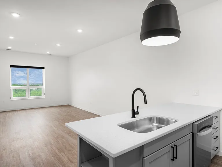 Modern open-concept space featuring a sleek kitchen with an elegant countertop and a bright living area with a large window offering scenic views. Modern open-concept space featuring a sleek kitchen with an elegant countertop and a bright living area with