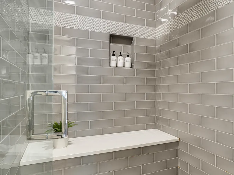 Spacious walk-in rainfall shower with a built-in bench, complemented by complimentary shampoo, conditioner, and body wash for a refreshing, spa-like experience.