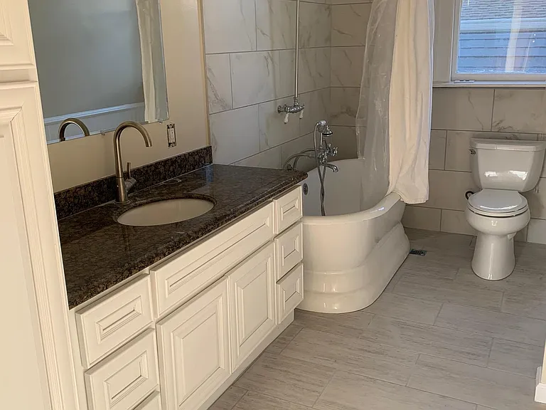 Remodeled bathroom with victorian style bath tub and ceramic tiled walls and floor
