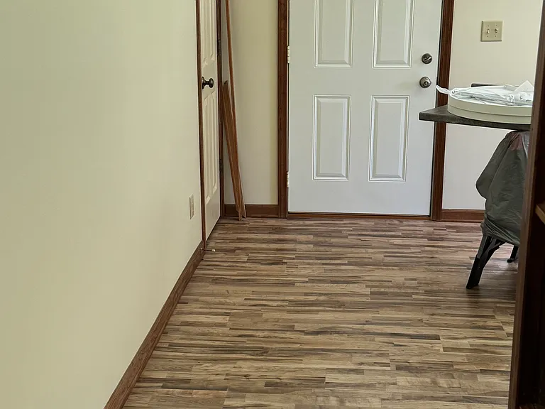 Living room with new flooring, door out to small deck and circle drive