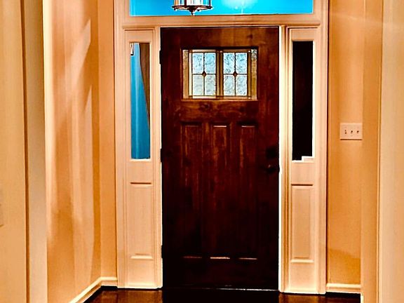 Beautiful Real Wood Espresso Stained Floor with English Designer Tattoo. Brass n Crystal Chandelier Light Designer Colors. High ceilings, Arches and Thick Moldings