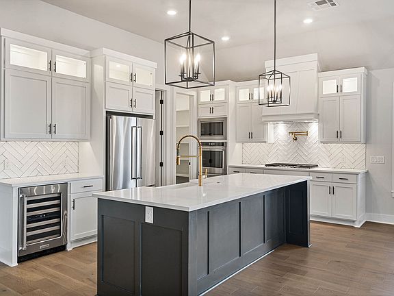 The upgraded kitchen has beautiful, white cabinetry and tile backsplash.