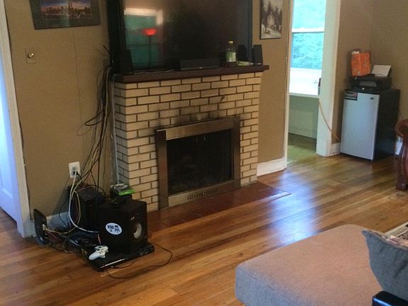 Living room with fireplace. View from door to screened porch. Shows entrance to kitchen annex.