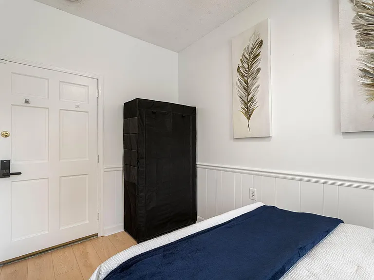 Bedroom space with wood-look flooring, wall art, and room for storage near the entry for easy everyday organization.
