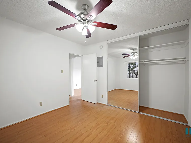 Bedroom with a Mirrored Closet, Ceiling Fan, and Vinyl Flooring
