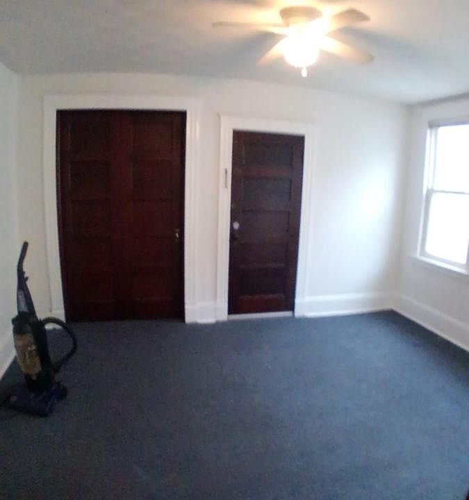 Large carpeted dining room with sliding door and ceiling fan