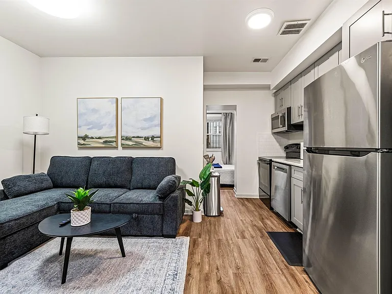 Open-concept living area flows into a streamlined kitchen with stainless-steel appliances, ample cabinetry, and durable floor