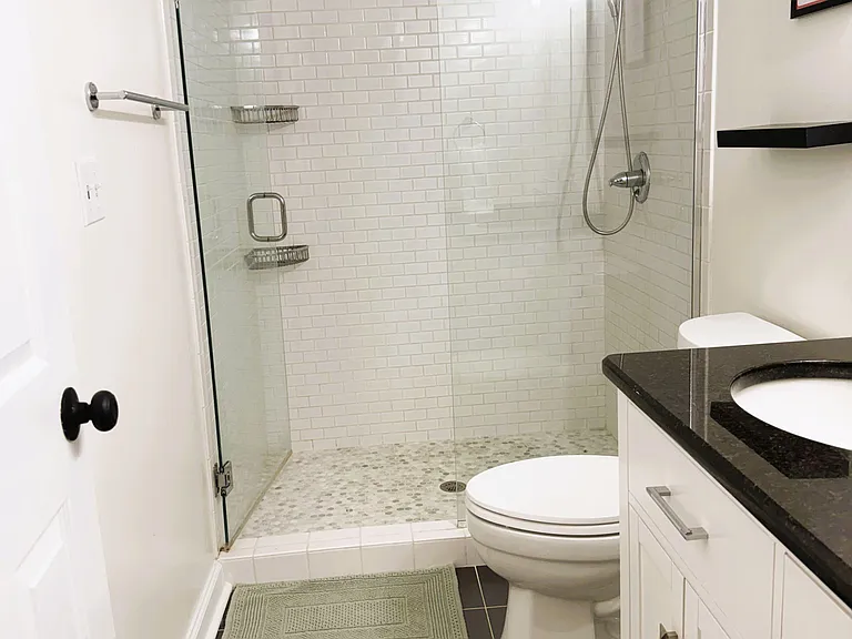 Updated bathroom with a glass-enclosed walk-in shower, tile surround, and a vanity with ample storage.