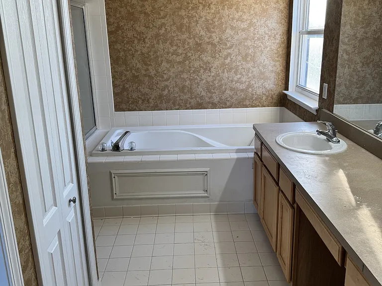 primary bathroom with tub, dual vanities & knee space- full width mirror & linen closet, commode and shower are hidden from view