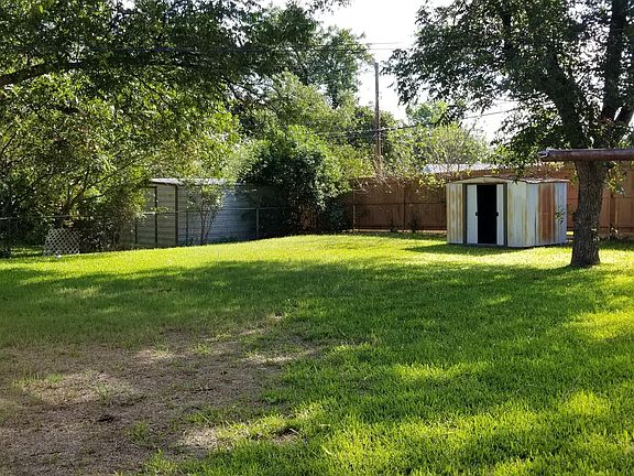 Backyard with small storage shed. Pecan tree, patio