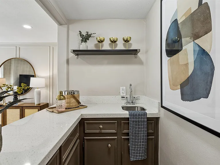 Wet bar featuring quartz countertops, a stainless steel sink with a chrome faucet, and dark cabinetry
