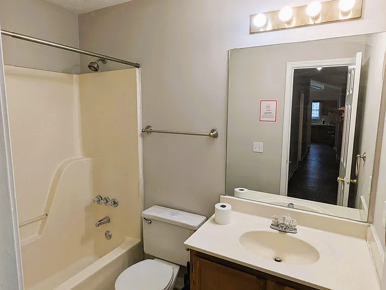Full bathroom with tub/shower combo, large wall mirror, and single-sink vanity with convenient storage.