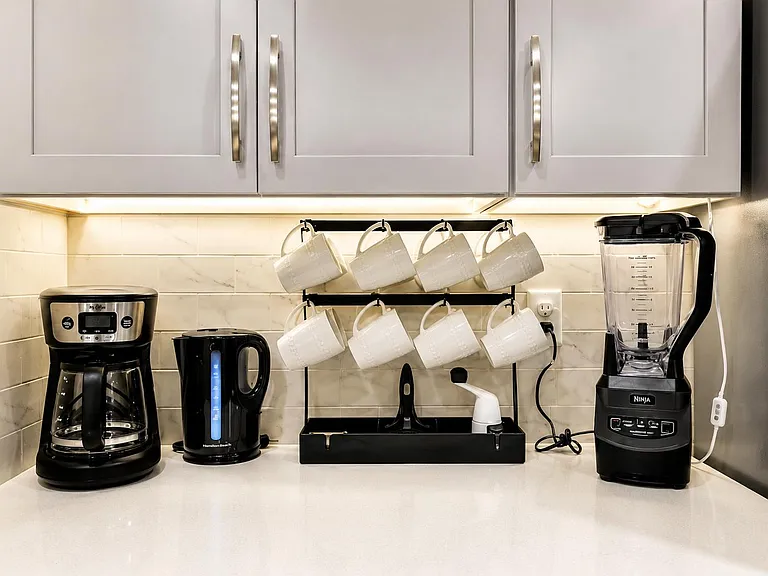 Kitchen counter station with upper cabinetry, tile backsplash, and ample prep space plus coffee/tea and small-appliance setup