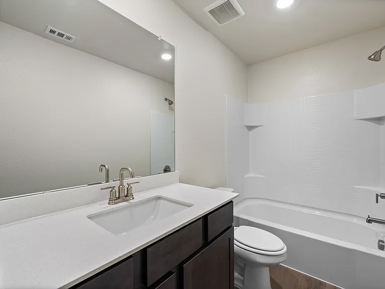 The secondary bathroom has a large vanity space and shower-tub combo.