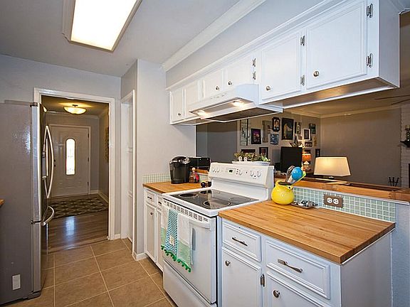 Open view of kitchen and living room. Butcher block counter tops with glass tile back splash.