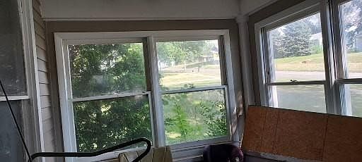View from inside the enclosed front porch looking south and east toward the street. This front porch extends the seasons, usable in early spring, all summer, and into autumn. Plywood is now part of the roof for the small back porch.