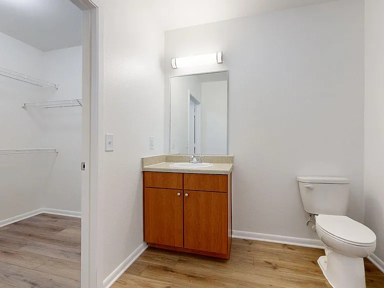 Apartment Bathroom with LED vanity mirror and wood-style floor.