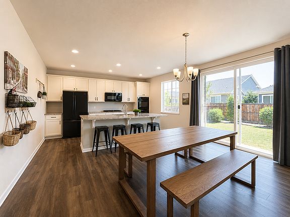 Shared kitchen and dining area with island seating, a large table and backyard access. Digitally enhanced for presentation.