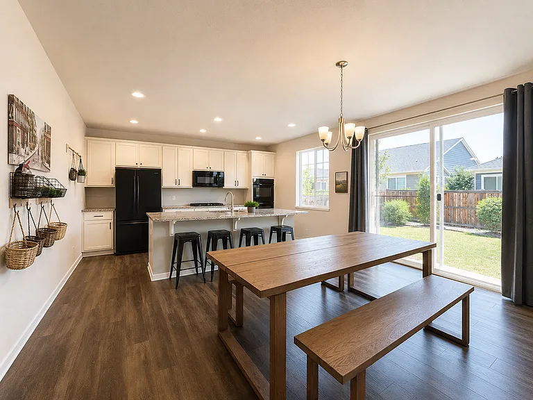 Shared kitchen and dining area with island seating, a large table and backyard access. Digitally enhanced for presentation.