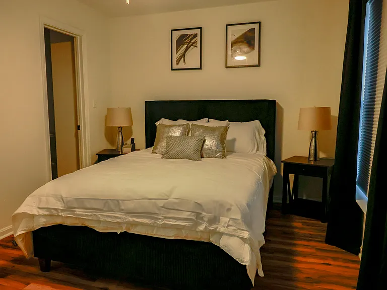 Generous primary bedroom with hardwood flooring, elegant finishes, and a 50-inch professionally mounted smart TV for a modern touch.