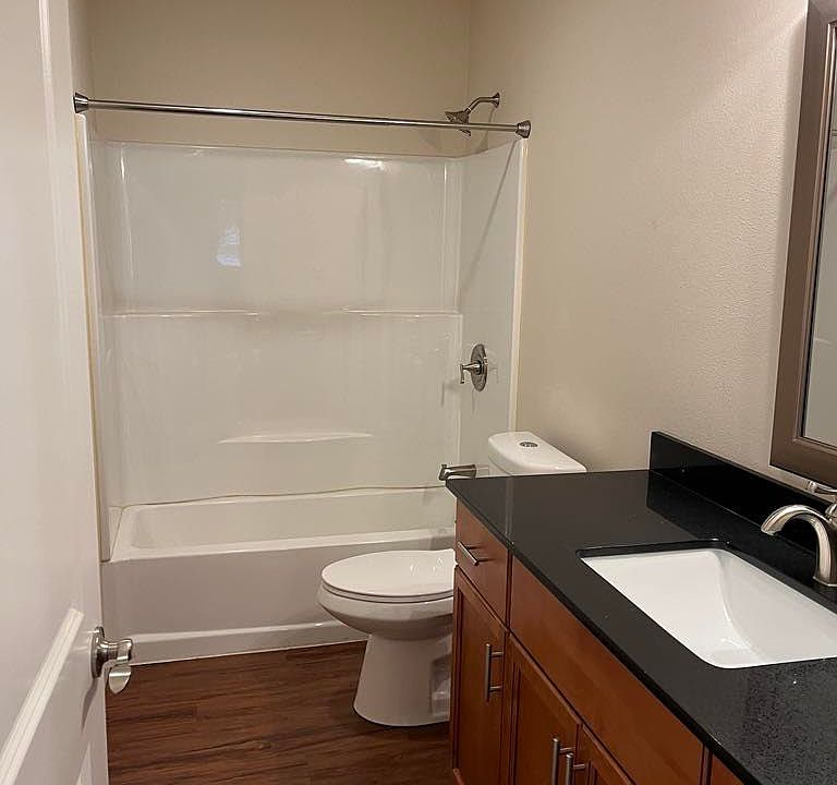 Bright bathroom with full tub and shower, modern vanity, and functional layout.