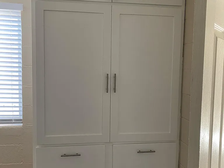The bedroom has a custom-made, 2-door armoire with several cabinets and drawers for clothes or linen.