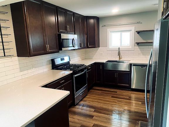 Kitchen features quartz counters, subway tile backsplash, and a brass faucet/drawer and door pulls.