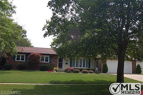 Front of home which sits on 1 1/2 lots and is framed by a white vinyl picket fence.