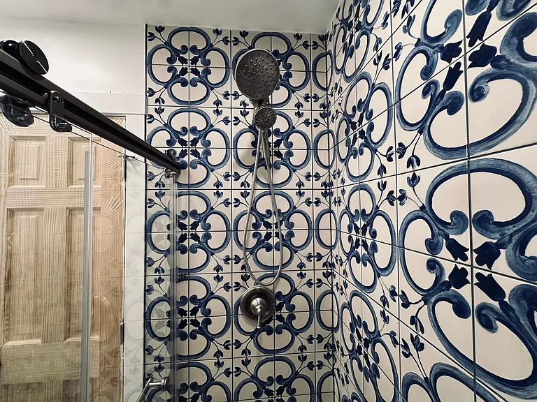 Newly renovated bathroom, walk in shower with rain shower head, handheld shower head, glass sliding door. Water saving toilet, beautiful marble vanity, Spanish wall tile. View of the shower head