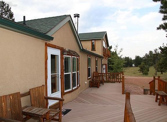 View of the front of the home with custom wood accents and furniture that stays with the home. Also notice the composite decking and flag stone walk way.