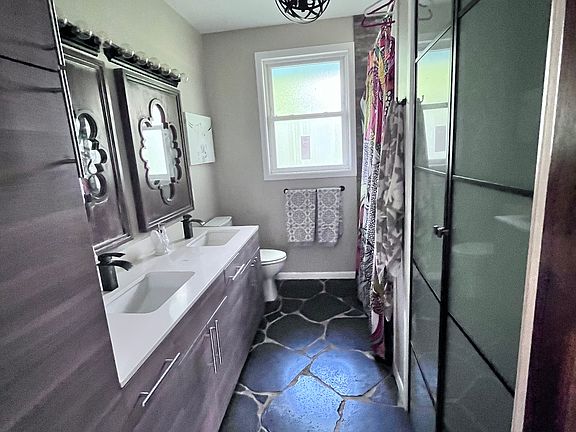 Master bathroom with lava rock flooring, ample cabintery, jetted tub with shower and closet.