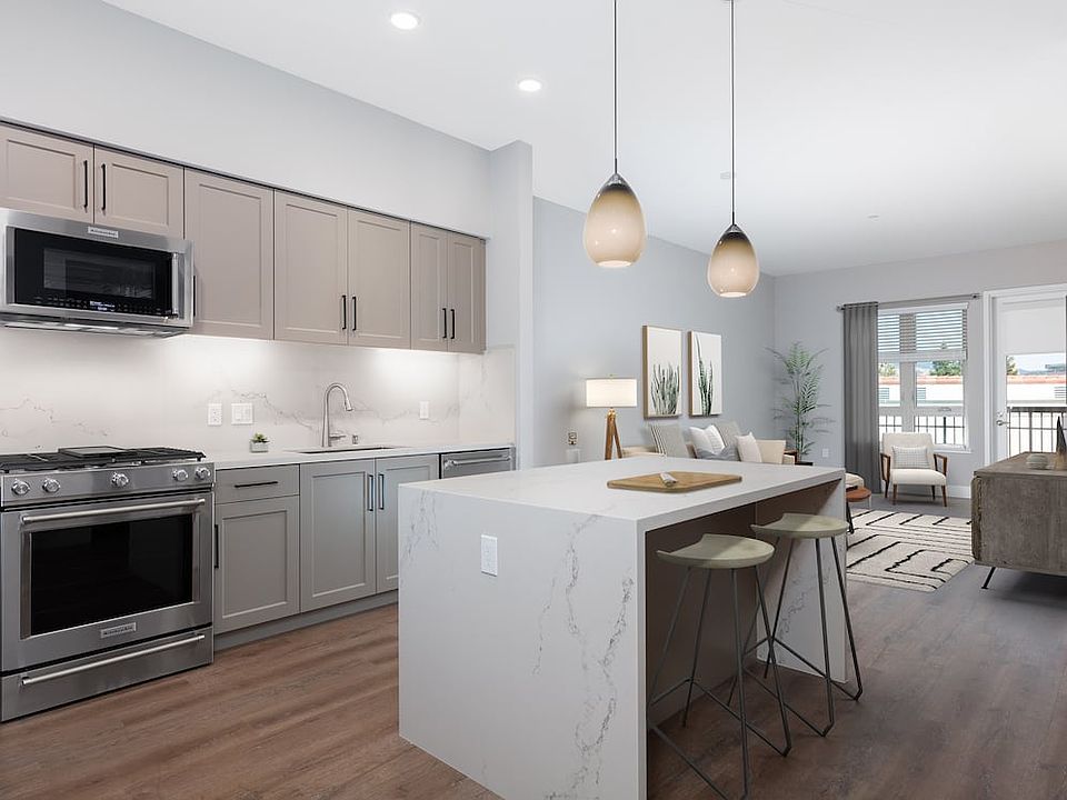 Signature Collection kitchen with upgraded stainless steel appliances, grey cabinetry, white marble countertops and backsplash, and hard surface flooring
