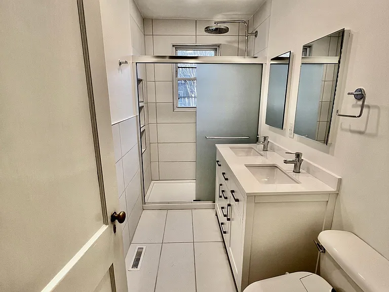 Renovated bathroom with walk-in shower featuring dual head system and double vanity