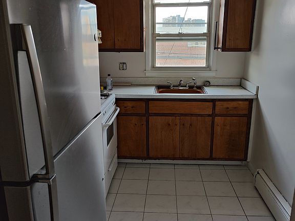 Bright and clean, this original hardwood kitchen features a gas range, externally vented range hood, and stainless steel refrigerator.