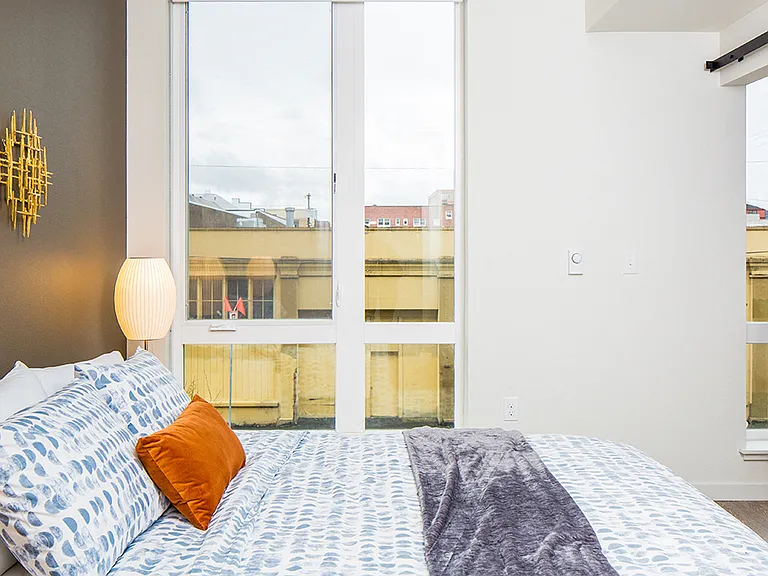 Bright bedroom with floor-to-ceiling windows and sweeping city views.