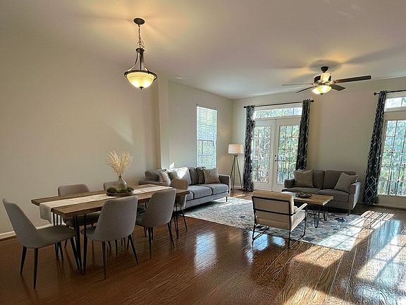 Living room and dining room combo with French glass doors, real hardwood floors, and celing light fixtures, and ceiling fan.

**This image is vitually staged with furniture, table setting, and aera rug for illustrative purposes.**
