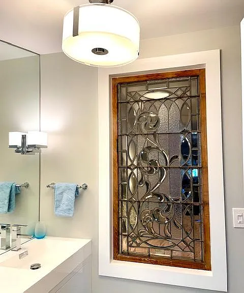 Reclaimed antique leaded glass window separates vanity area from bedroom
