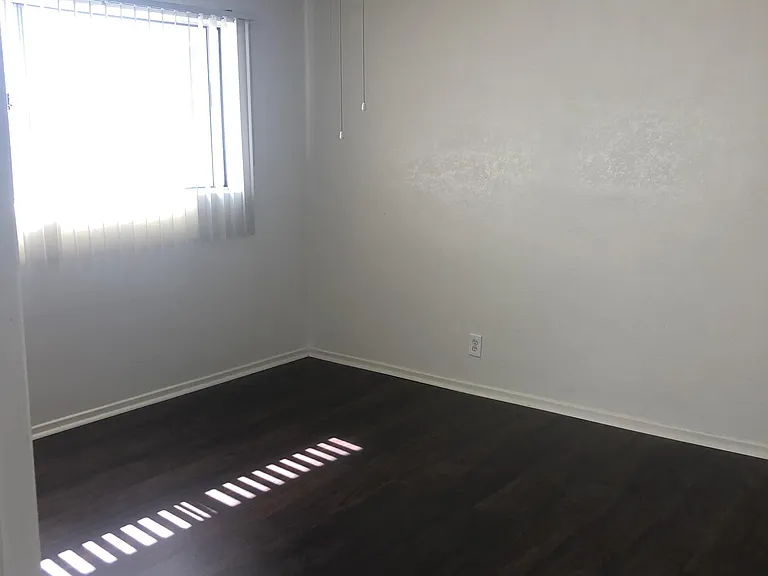 Master bedroom vertical blinds, hardwood flooring, ceiling fan and large closet.