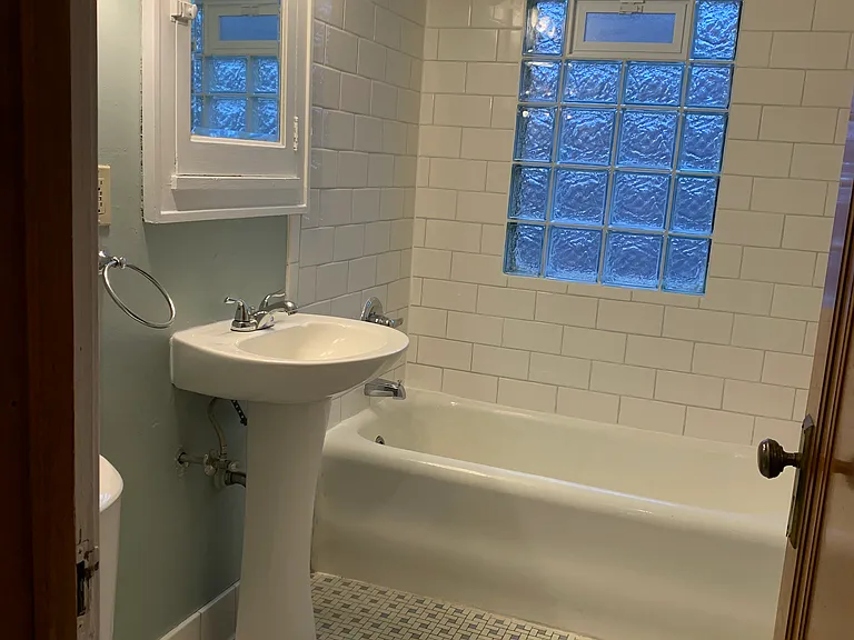 Bathroom with pedestal sink and tile shower over bath