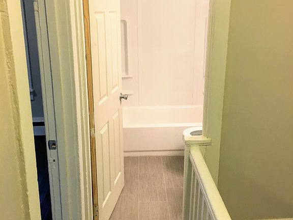 Facing bathroom from living room area; entrance to bedroom on left; stairs to lower level on right