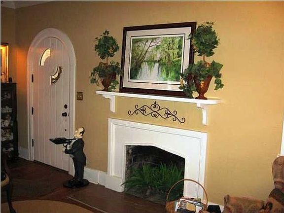Formal living room with very simple fireplace. Note arched front door.