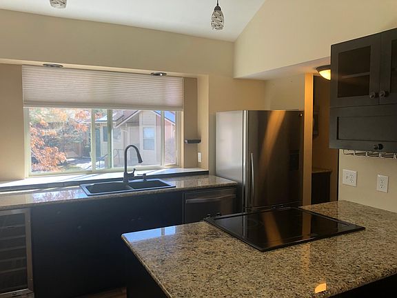 Granite countertops drop in electric range with wine fridge and cabinet.