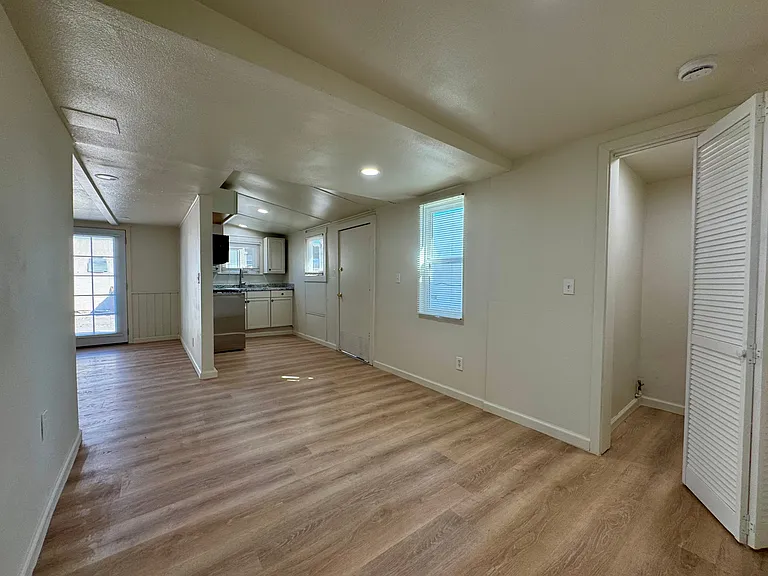 Dining room off of the living room with a view of the kitchen and laundry closet.