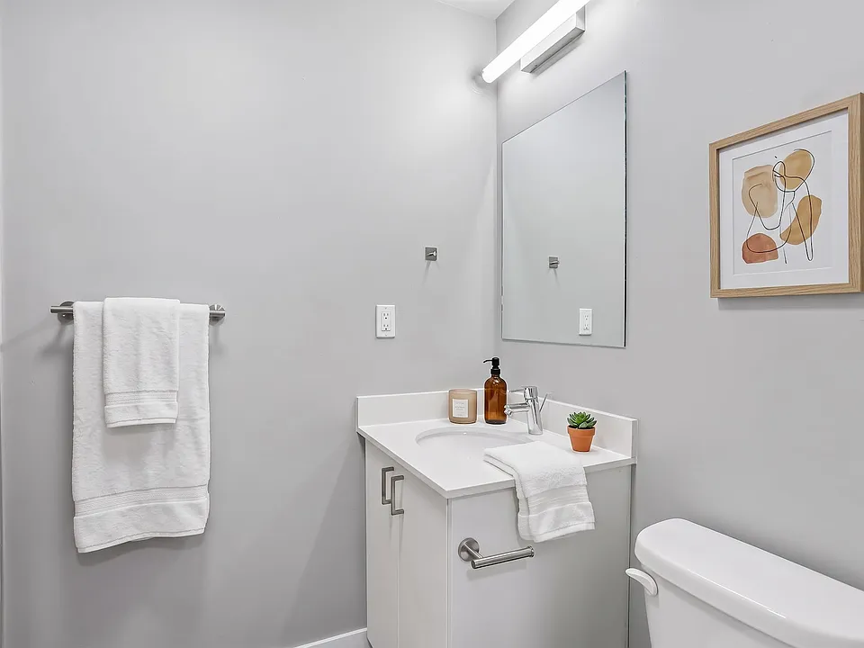 A bright, clean bathroom with a tiled shower and a vanity with real storage.