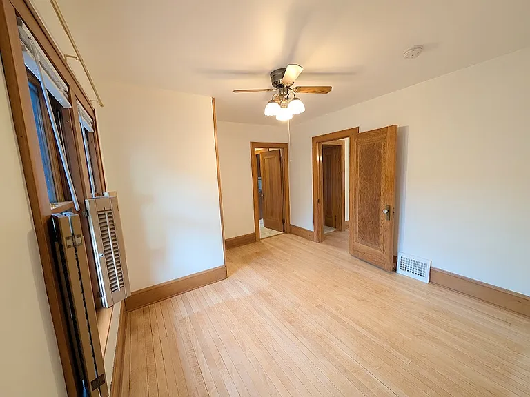 [UPPER UNIT]: First bedroom with shutter style window covers and blinds. Double sized closet