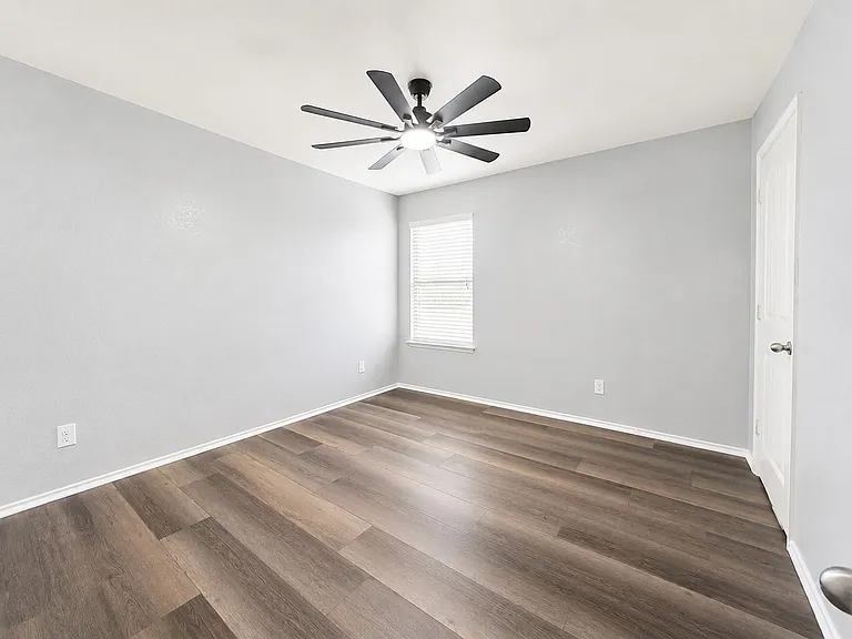 Room featuring wood-finish flooring, a modern ceiling fan, and a window with blinds