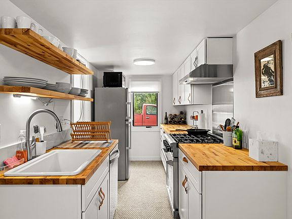 Galley Kitchen with Oversized Sink, Dishwasher, Gas Range, Vent Hood Butcher Block Counter Tops and Open Shelving