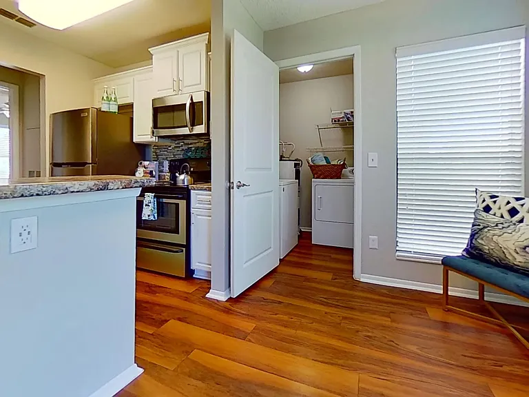 The Martinique Autograph floor plan showcases a modern kitchen with stainless steel appliances, adjacent to a convenient in-unit laundry room. Enjoy the blend of style and functionality in this beautiful space.