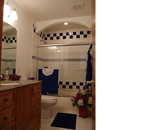 Main floor bath with large vanity, ceramic tile floors and shower with archway