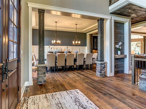 Spacious dining room features the reclaimed barn wood floors, high wainscoting, double chandeliers and rustic stone and wood tim